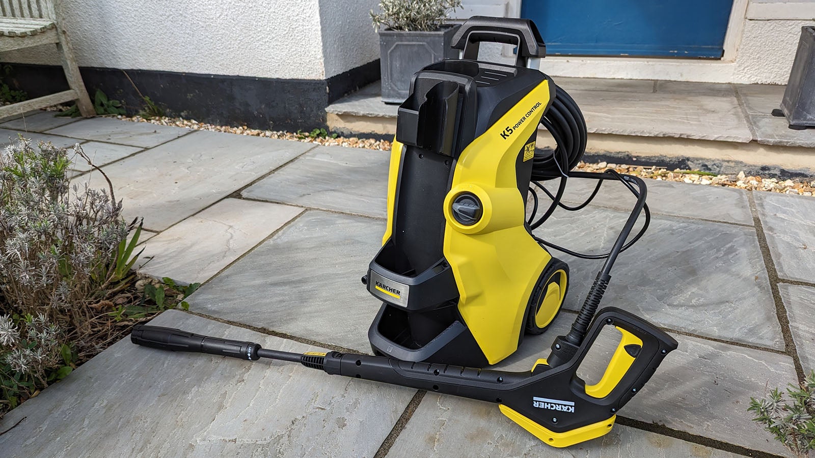 Kärcher K5 Power Control montada con la lanza y la manguera desplegadas sobre una terraza de piedra
