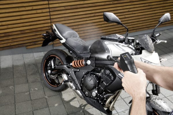Persona usando la pistola Smart Control de Kärcher para lavar una moto negra