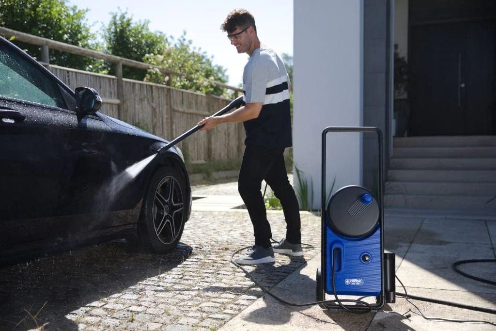 Persona lavando un coche negro en casa con hidrolimpiadora Nilfisk Core